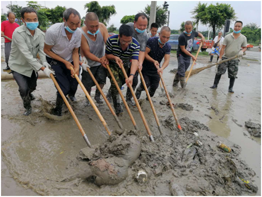 01 农工党金堂县总支负责人罗灵聪（左4）带领人员清洗街上的淤泥.png